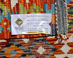 A handwoven Afghan Maimana kilim featuring a vibrant geometric pattern in wool.