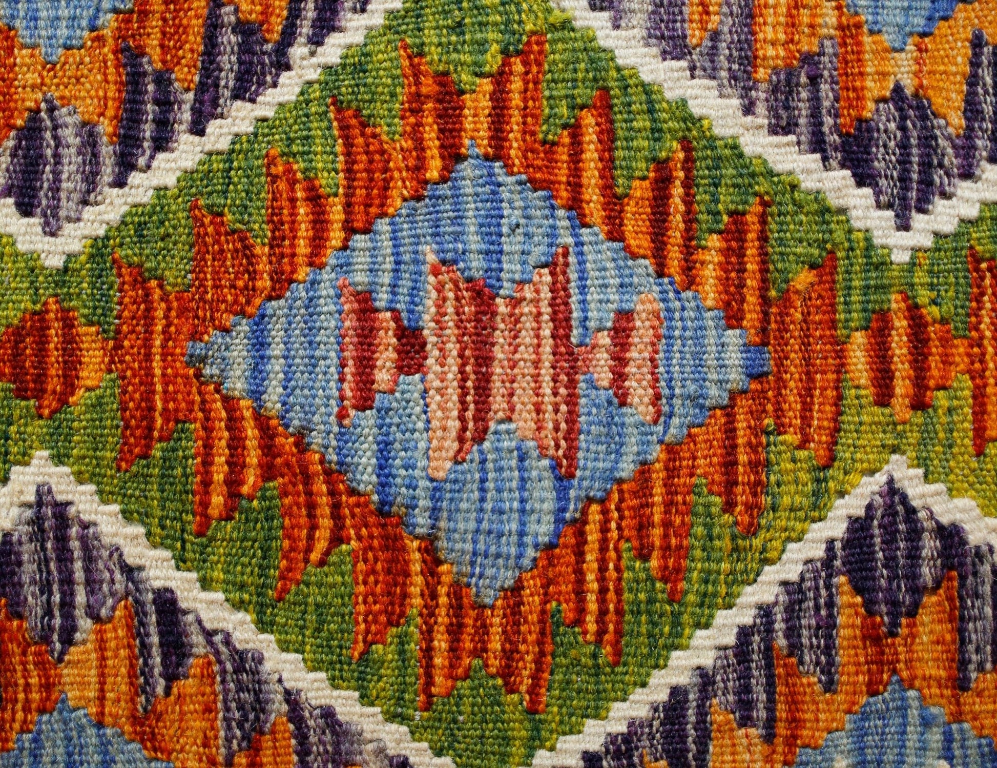 A handmade Afghan Maimana kilim featuring a vibrant geometric pattern in wool.