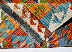 A close-up view of a handwoven Afghan Maimana kilim featuring vibrant geometric patterns in wool.