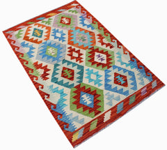 Handwoven Afghan Maimana kilim rug featuring a colorful geometric diamond pattern on a cream base.