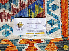 A handmade Afghan Maimana kilim rug featuring a vibrant geometric pattern in blue, orange, and red.