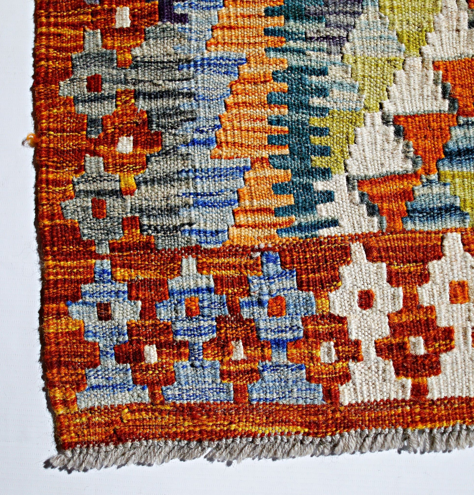 A handwoven Afghan Maimana kilim featuring a vibrant geometric pattern in wool.