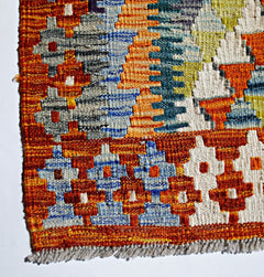 A handwoven Afghan Maimana kilim featuring a vibrant geometric pattern in wool.