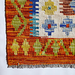 Handwoven Afghan Maimana kilim featuring geometric patterns in vibrant orange, blue, and yellow.