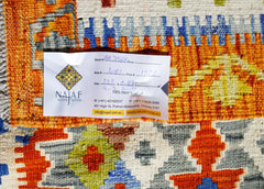 A handwoven Afghan Maimana kilim featuring a vibrant geometric pattern in orange, blue, and grey.