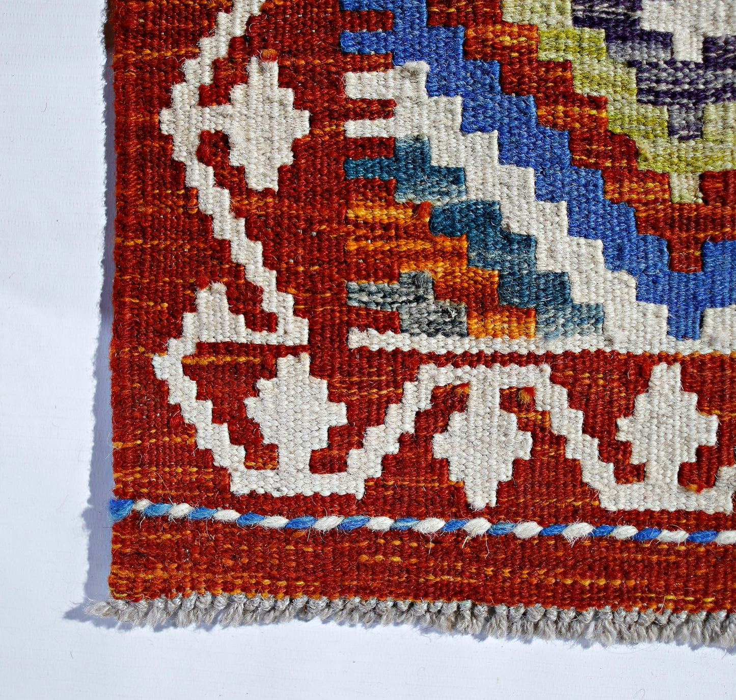 Handwoven Afghan Maimana kilim featuring geometric patterns in vibrant red, blue, and white wool.