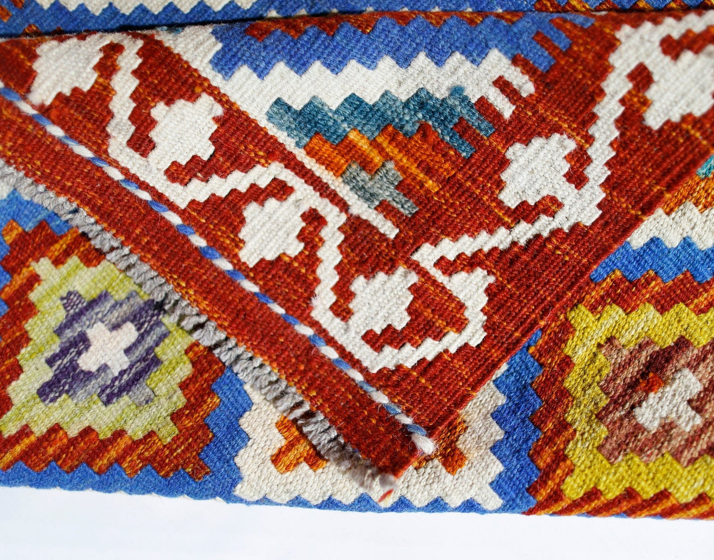 A close-up of a handwoven Afghan Maimana kilim featuring vibrant geometric patterns in wool.