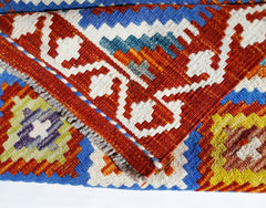 A close-up of a handwoven Afghan Maimana kilim featuring vibrant geometric patterns in wool.