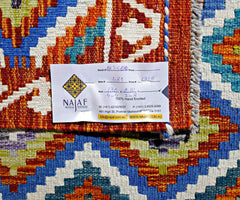 An Afghan Maimana Kilim rug featuring vibrant geometric patterns in blue, orange, and white.
