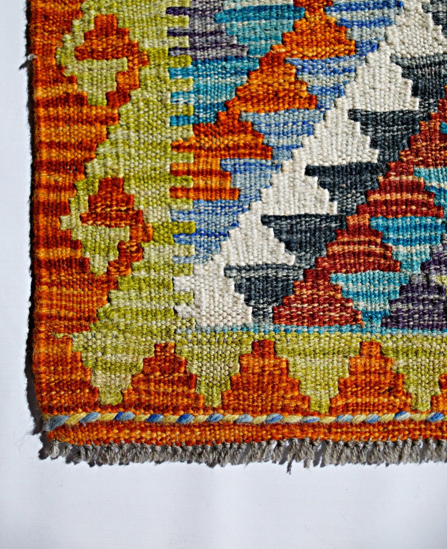 A handmade Afghan Maimana kilim featuring a vibrant geometric pattern in wool.