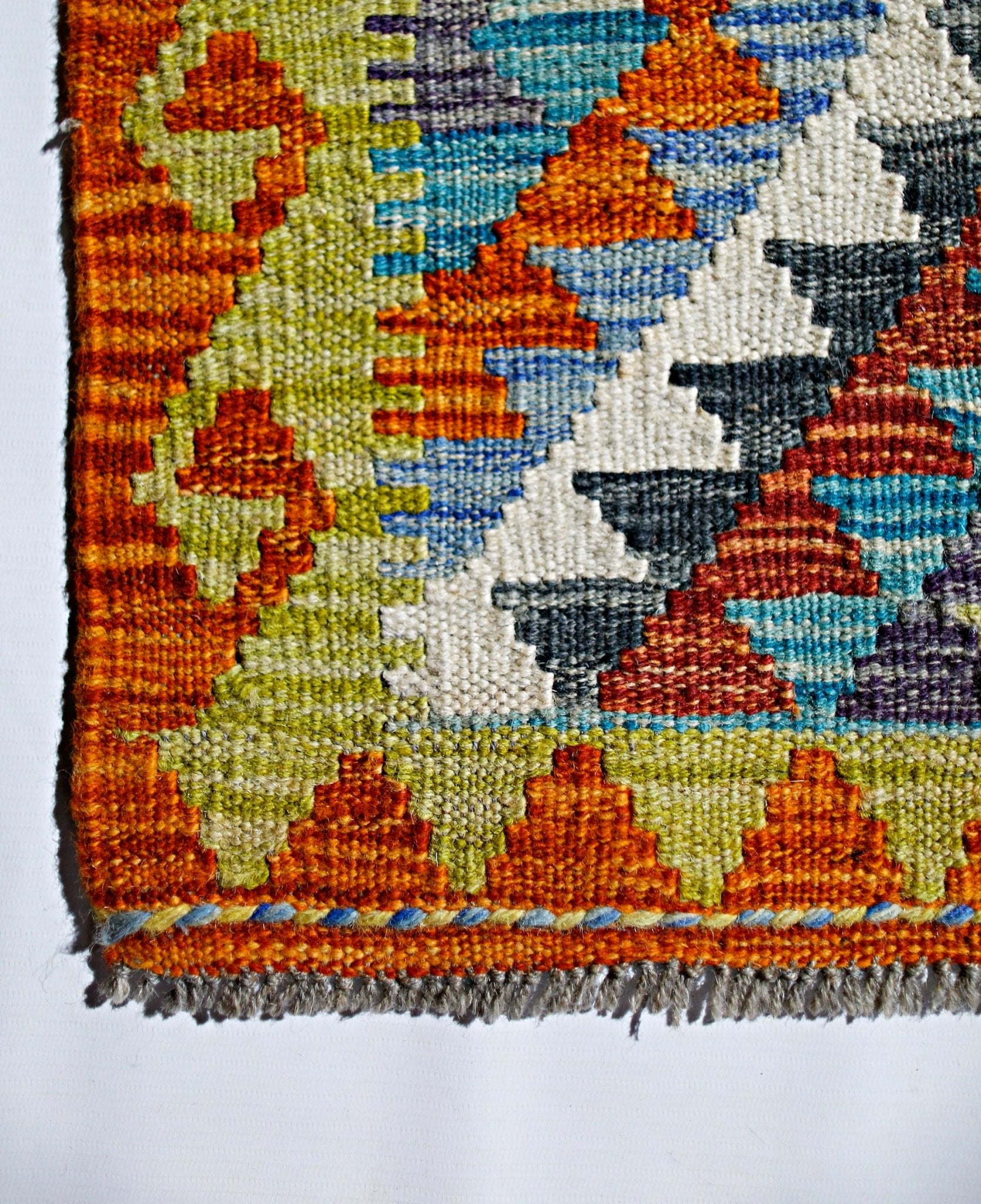 A handmade Afghan Maimana kilim featuring a vibrant geometric pattern in wool.