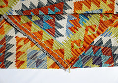 A handmade Afghan Maimana kilim rug featuring a vibrant geometric pattern in wool.