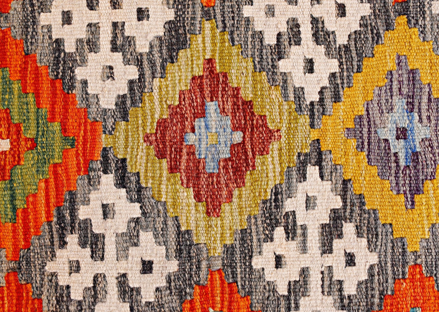 A handmade Afghan Maimana kilim featuring a vibrant geometric pattern in wool.