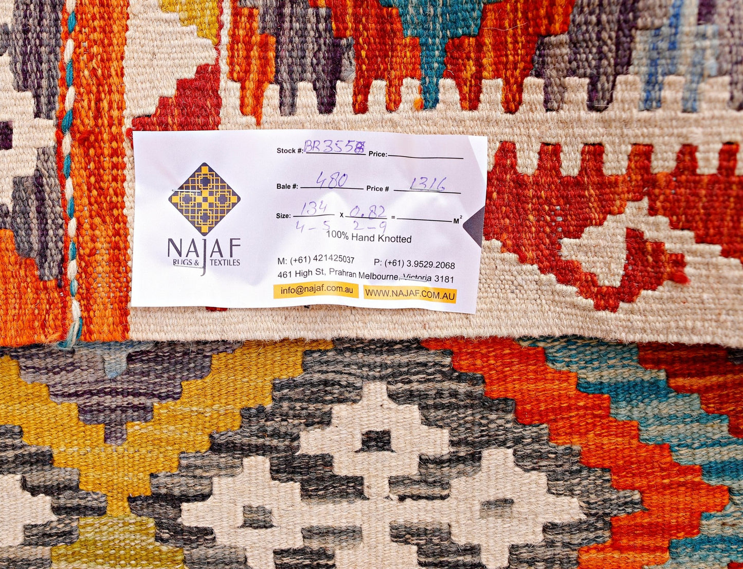 A handmade Afghan Maimana kilim featuring a vibrant geometric pattern in wool.