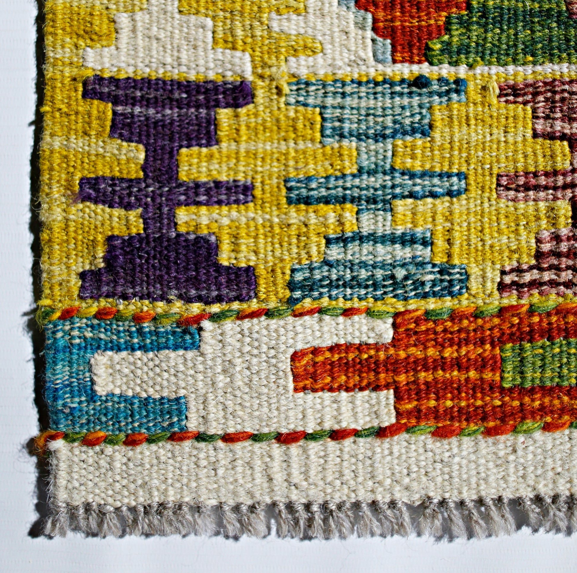 A handmade Afghan Maimana kilim featuring a geometric pattern in vibrant wool colors.