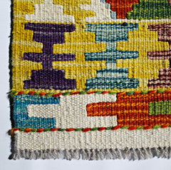 A handmade Afghan Maimana kilim featuring a geometric pattern in vibrant wool colors.