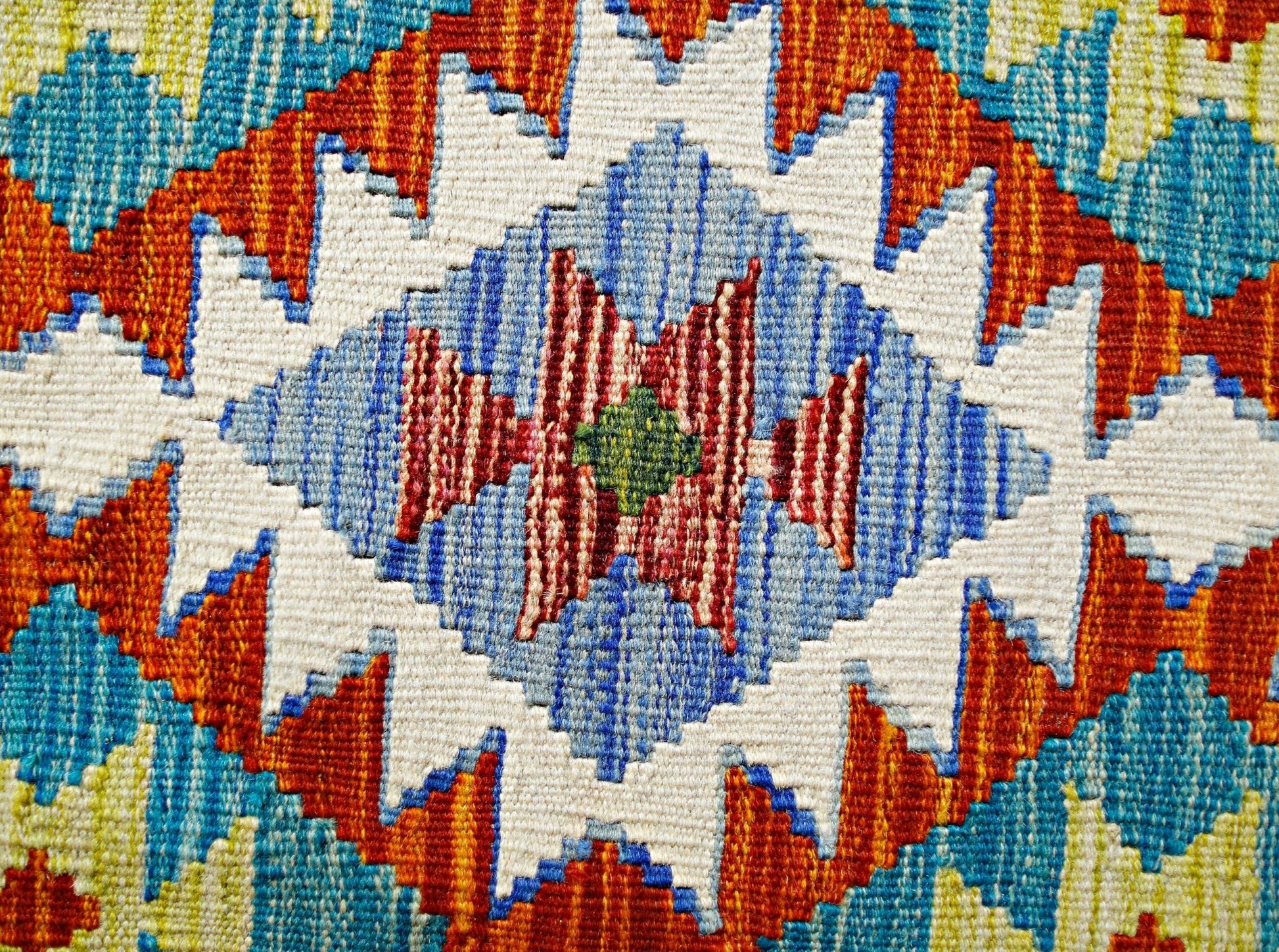 A close-up of a handmade Afghan Maimana kilim featuring a vibrant geometric diamond pattern.