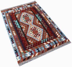 Handwoven Afghan Maimana kilim rug featuring geometric diamond patterns in red, blue, and brown.