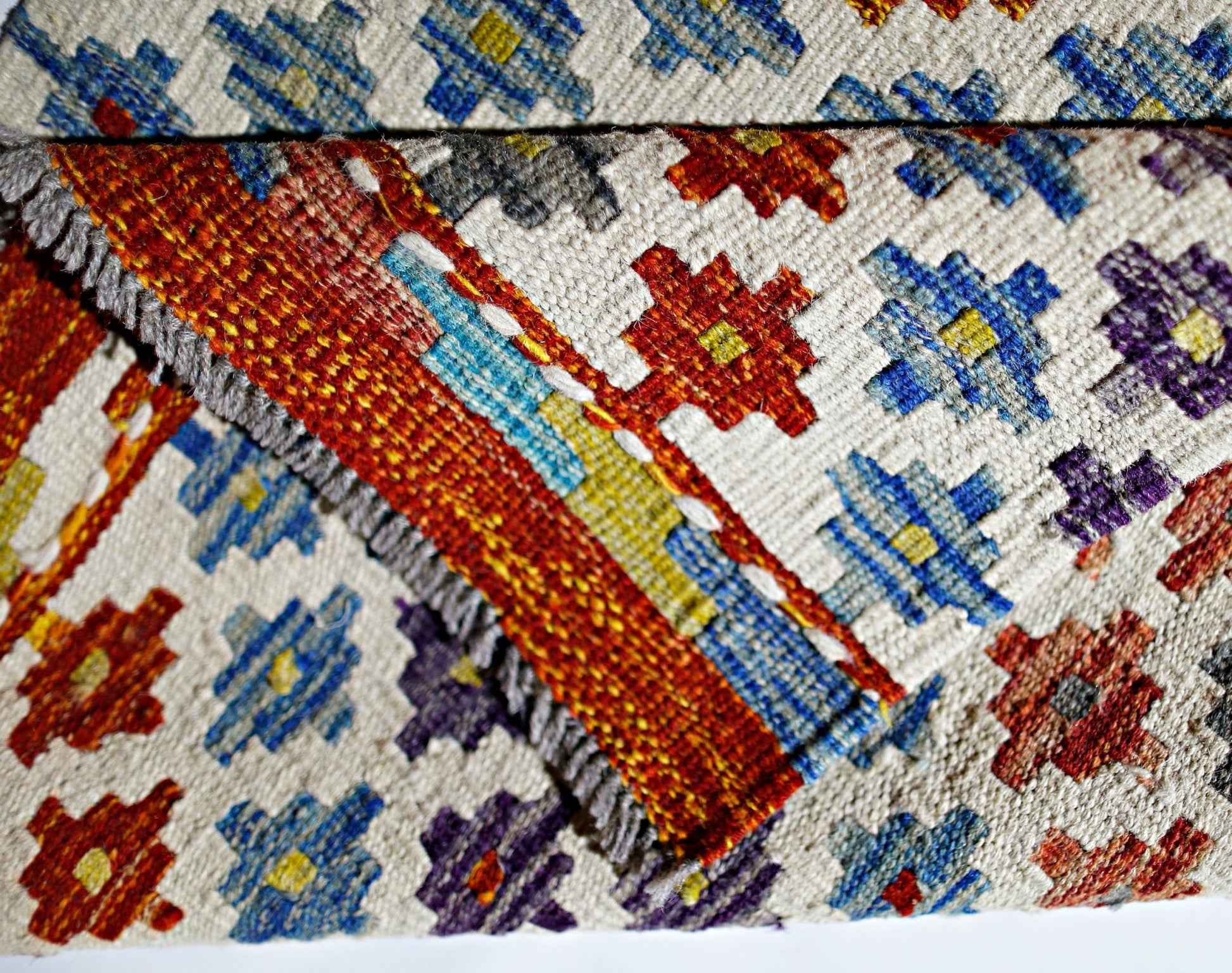 A handmade Afghan Maimana kilim featuring a geometric pattern in vibrant wool colors.