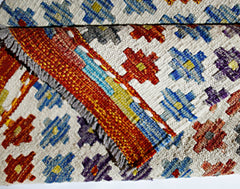 A handmade Afghan Maimana kilim featuring a geometric pattern in vibrant wool colors.