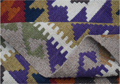 A handmade Afghan Maimana kilim featuring a geometric pattern in vibrant wool colors.