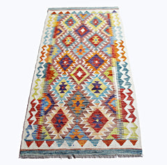 A rectangular, handwoven Afghan Maimana kilim rug featuring a vibrant, multicolored geometric pattern.