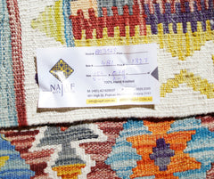A handwoven Afghan Maimana kilim featuring vibrant geometric patterns in wool.