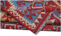 A handwoven Afghan Maimana kilim rug featuring geometric patterns in red, blue, and purple wool.