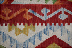 A close-up of a handmade Afghan Maimana kilim featuring geometric patterns in red, blue, and yellow.