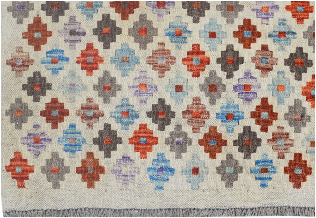 Handmade Afghan Maimana kilim rug featuring a repeating geometric pattern in vibrant colors.