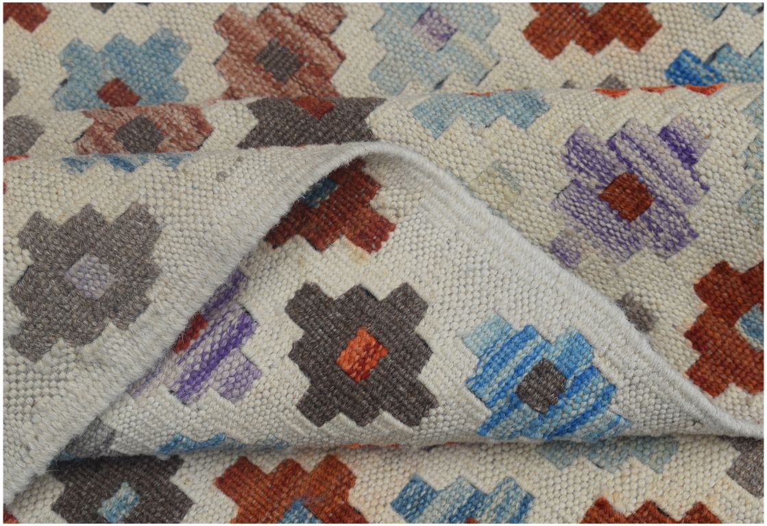 A handmade Afghan Maimana kilim rug featuring a geometric pattern in vibrant, multicolored wool.