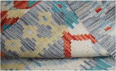 A handwoven Afghan Maimana kilim rug featuring a geometric pattern in red, blue, and yellow.