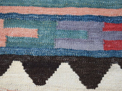A close-up of a handmade Afghan Maimana kilim featuring geometric patterns in wool.