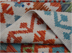 A handwoven Afghan Maimana kilim rug featuring a geometric pattern in orange, blue, and green.