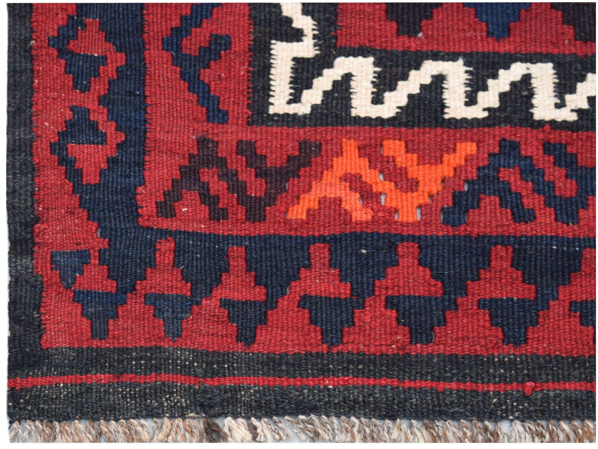 A close-up of a handmade Afghan Maimana kilim featuring geometric patterns in red, blue, and white.