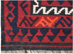 A close-up of a handmade Afghan Maimana kilim featuring geometric patterns in red, blue, and white.
