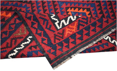 A handmade Afghan Maimana kilim featuring a geometric pattern in red, blue, and orange wool.