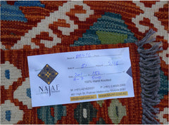 A handwoven Afghan Maimana kilim featuring a geometric pattern in shades of orange, blue, and green.