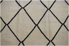 A beige kilim rug with a black diamond pattern.