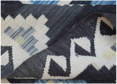 A handmade Afghan Maimana kilim rug featuring a geometric pattern in black, white, and blue.