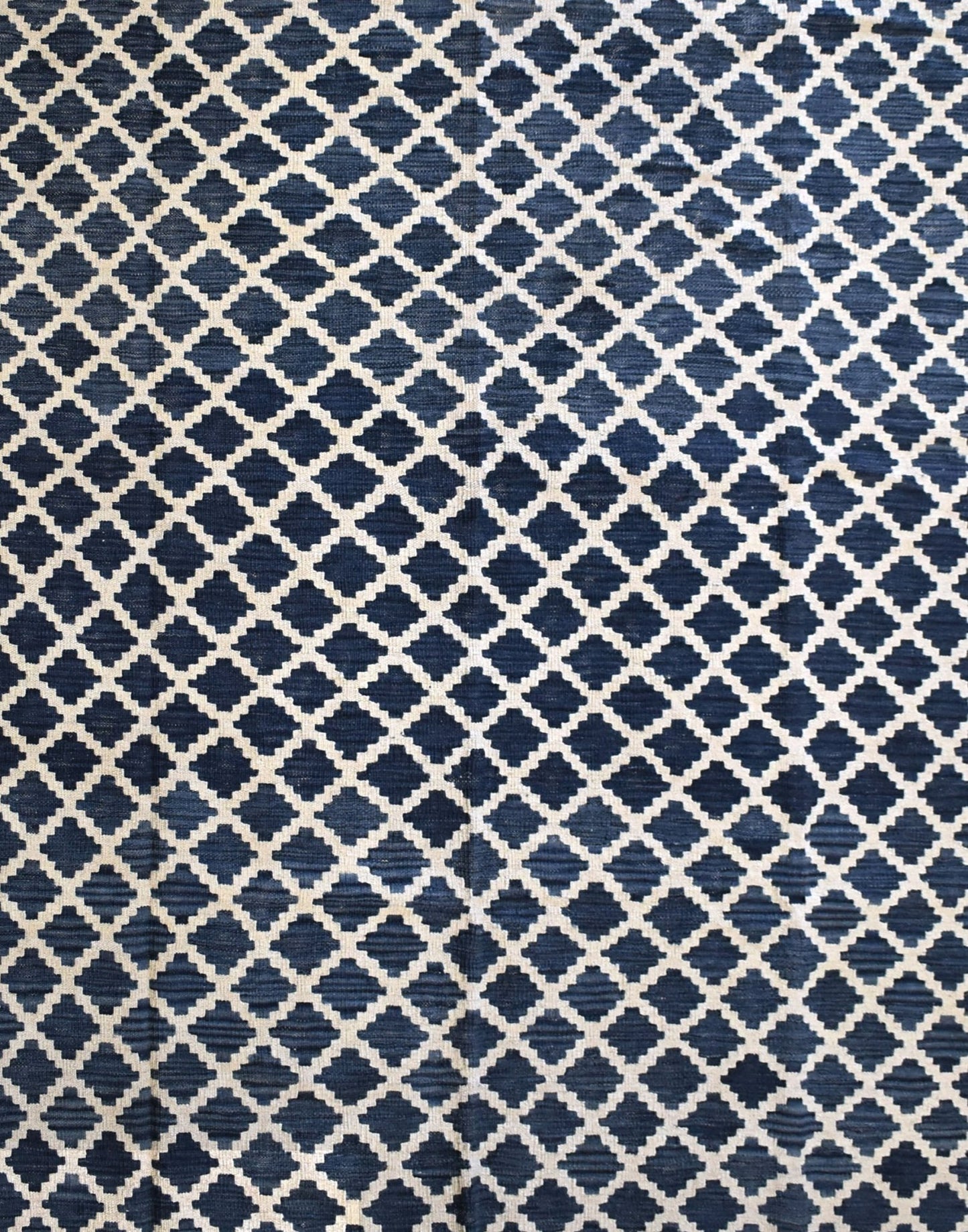 Handmade Afghan Maimana kilim rug featuring a repeating dark blue and cream geometric pattern.