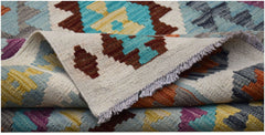 A handwoven Afghan Maimana kilim rug featuring a colorful geometric pattern on a cream background.