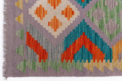 Handwoven Afghan Maimana kilim rug featuring a geometric pattern in vibrant multicolored wool.
