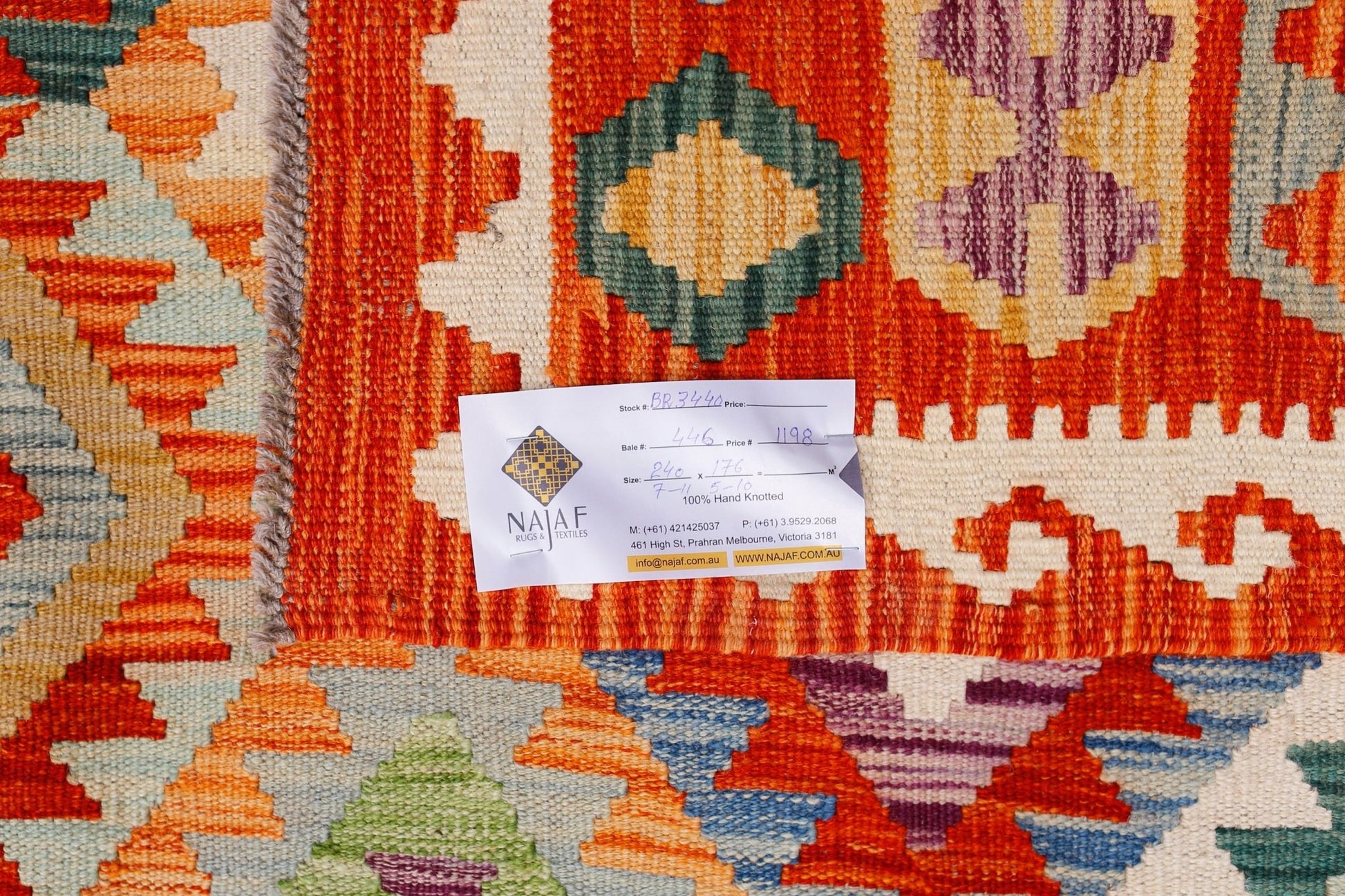 A handwoven Afghan Maimana kilim featuring a vibrant geometric pattern in orange, purple, and blue.