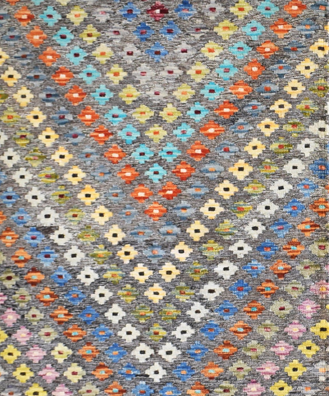 Handmade Afghan Maimana Kilim rug featuring a colorful geometric pattern on a grey background.
