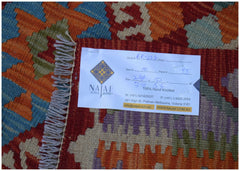 A flatwoven Afghan Maimana kilim featuring a vibrant geometric pattern in red, blue, and orange.