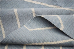 A handwoven Afghan Maimana kilim rug featuring a light blue field with cream geometric stripes.