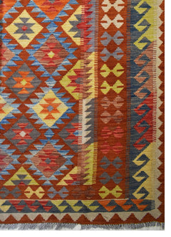 Handmade Afghan Maimana kilim rug featuring a vibrant geometric pattern in warm earth tones.