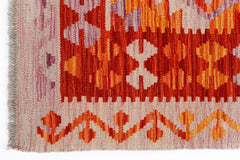 Handwoven Afghan Maimana kilim featuring geometric patterns in shades of red, orange, and cream.