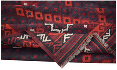 A folded Afghan Maimana kilim featuring a geometric pattern in deep red, black, and cream wool.